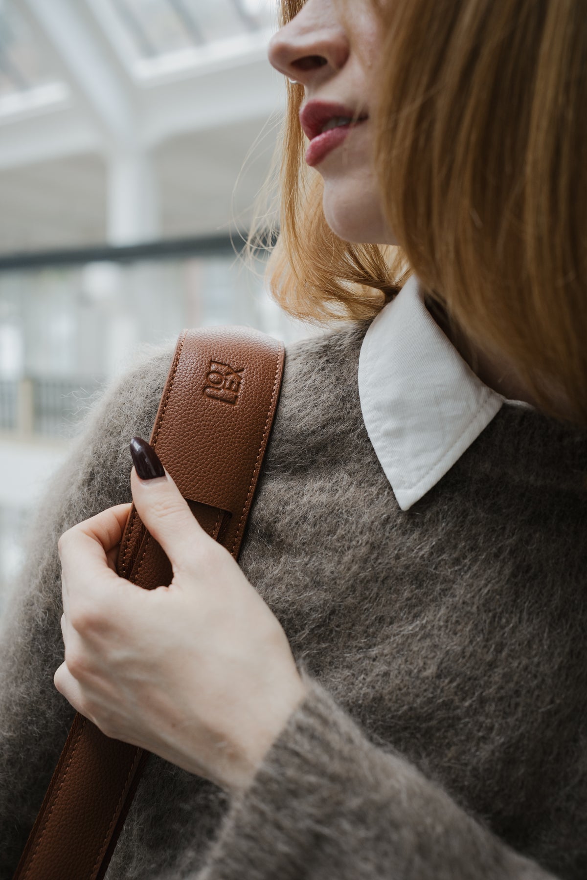 Person holding a brown leather bag with a blurred background