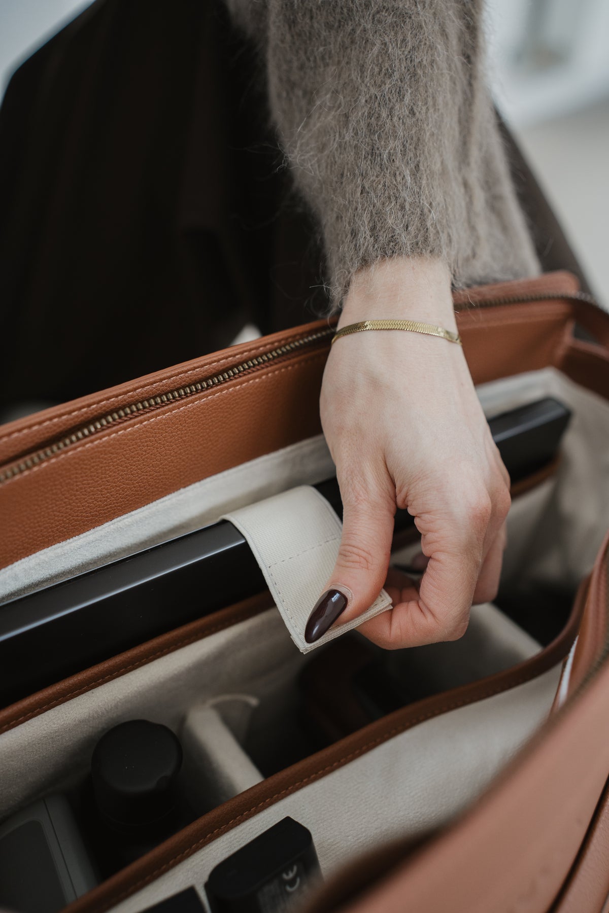 Hand opening a suitcase with a focus on the action of pulling the handle.