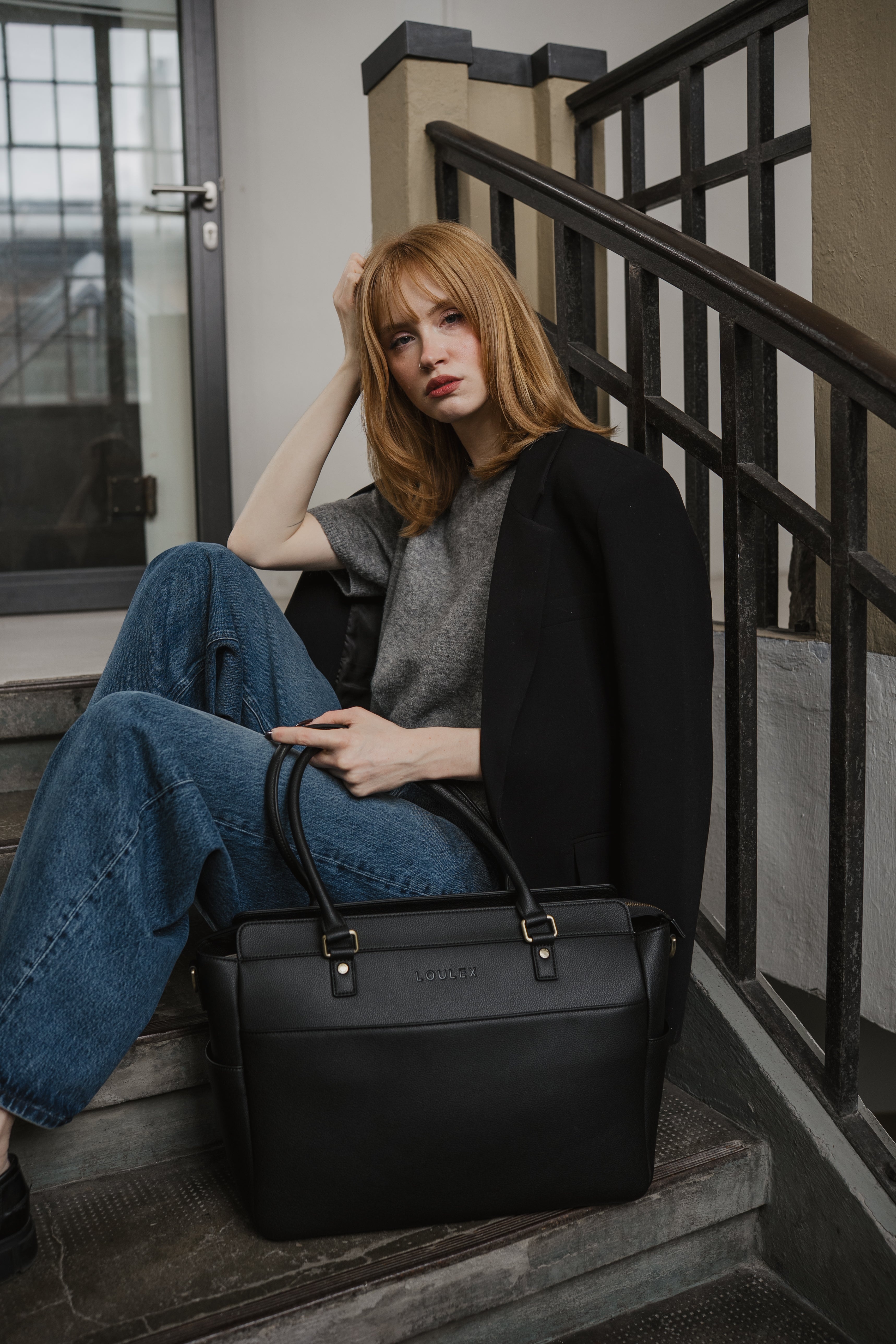 Woman sitting on stairs holding a black leather bag