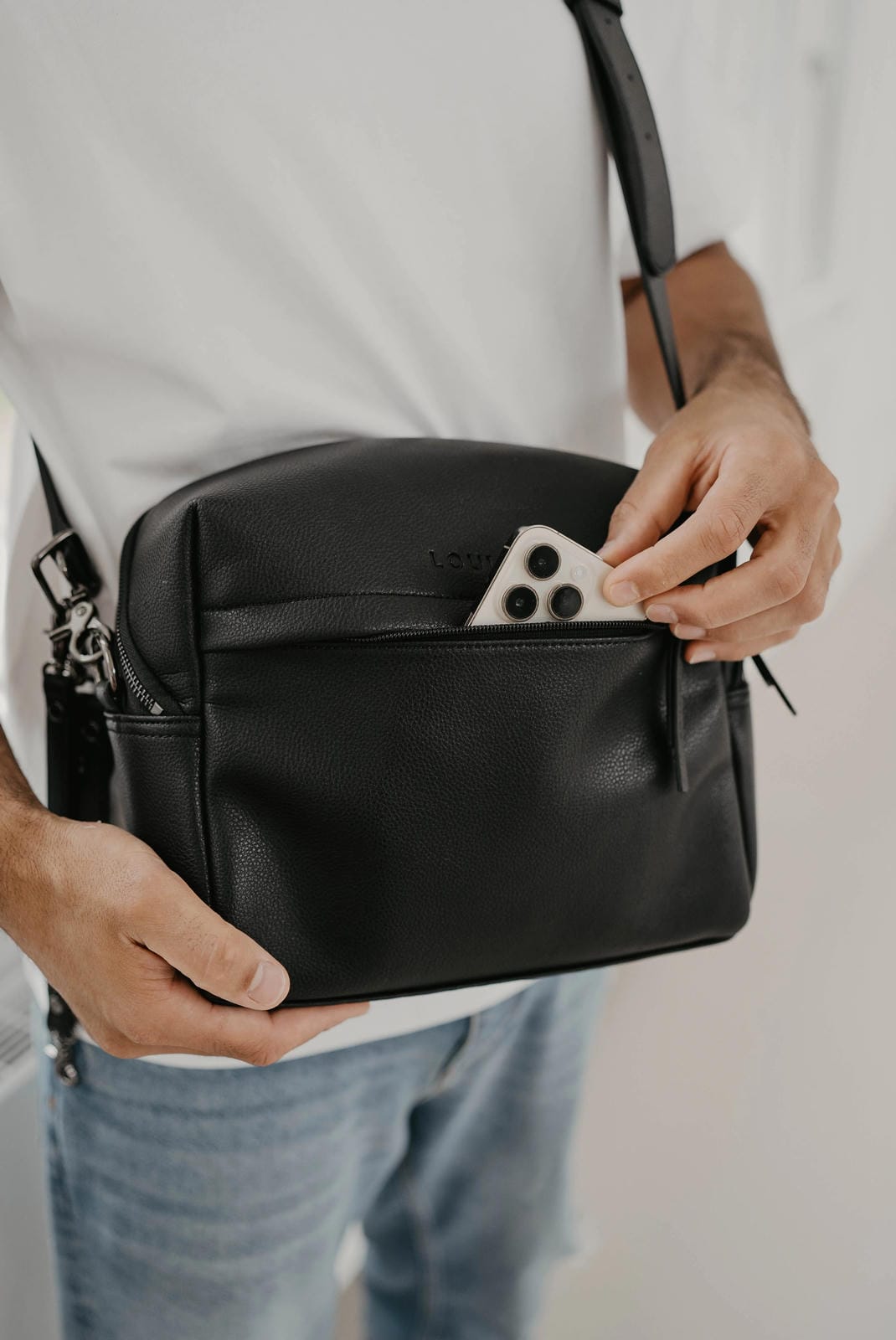 Person holding a black leather bag with a blurred background