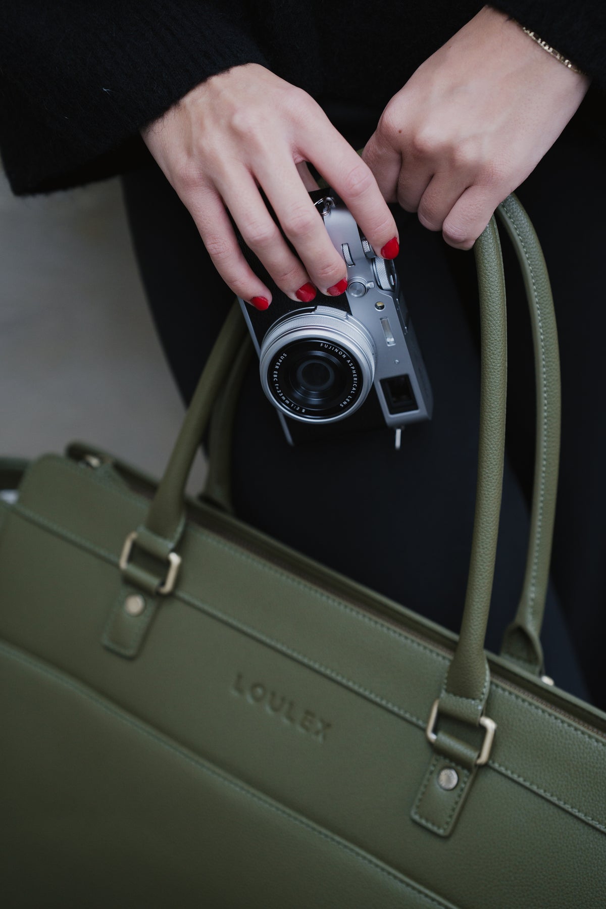 Person holding a camera with a green handbag in the foreground