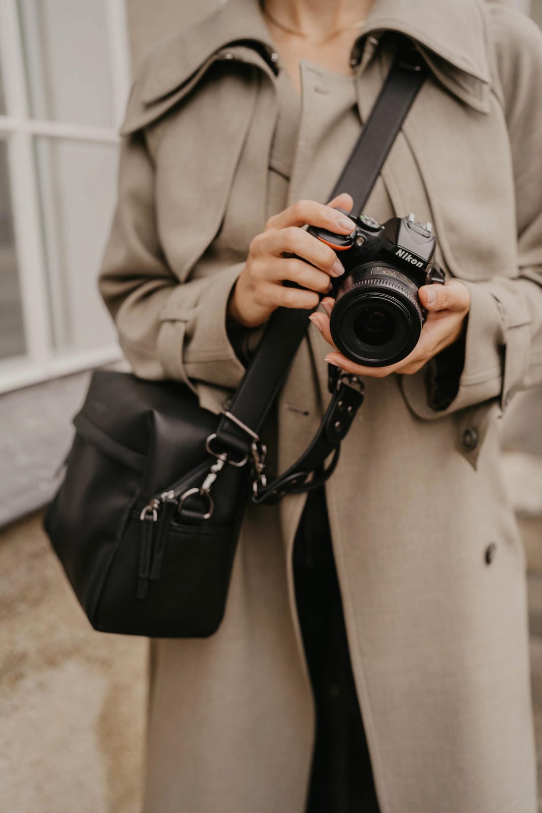 Person holding a camera with a black bag over shoulder
