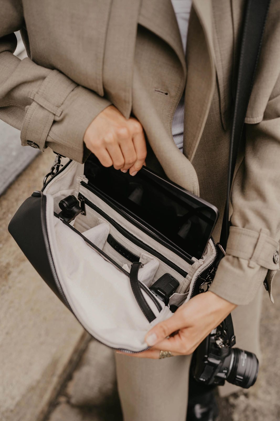 Person holding a camera bag with a camera inside, wearing a coat.
