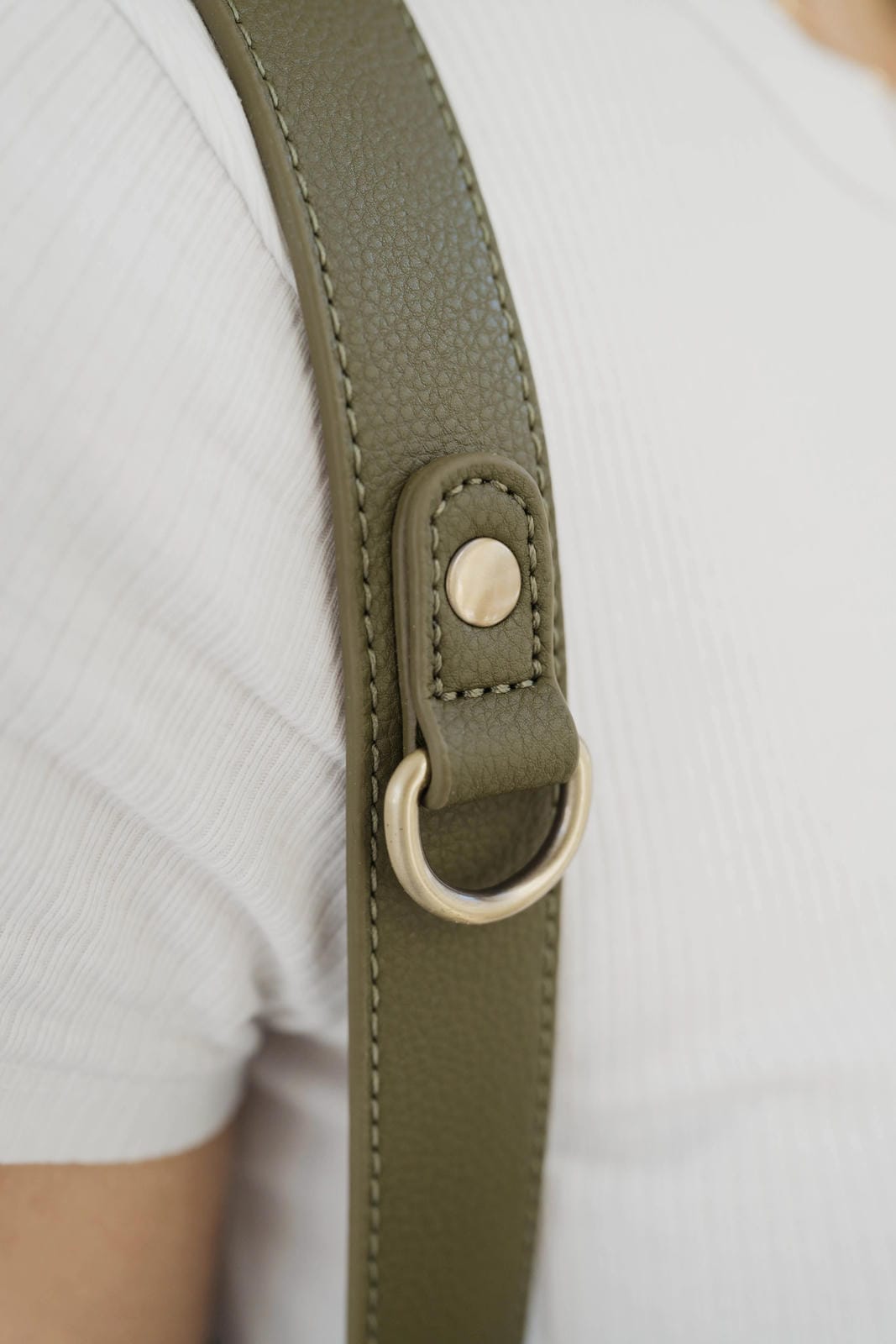 Close-up of a green strap with a metal ring on a white background