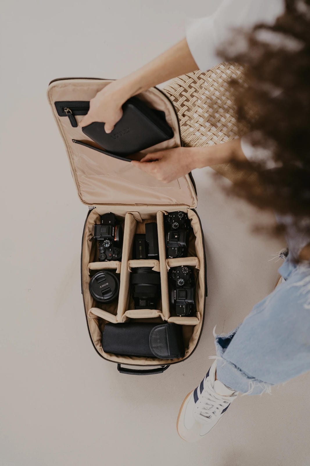 Person opening a camera bag with multiple cameras inside on a light background