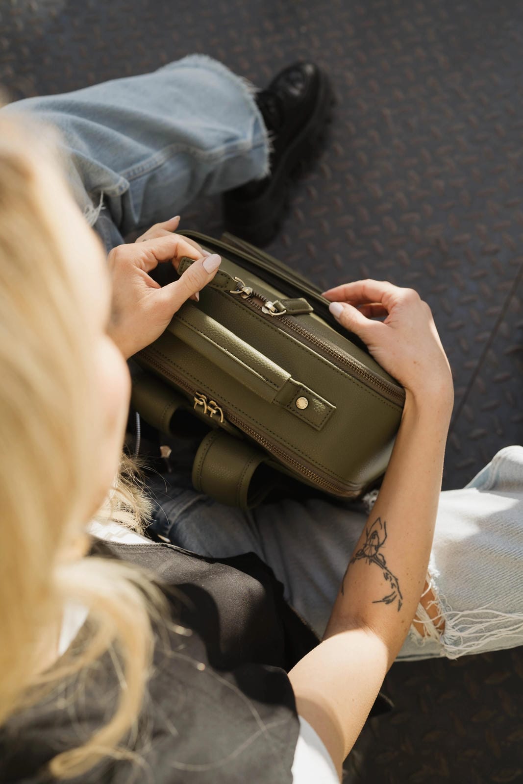 Person sitting on a couch holding a green handbag.