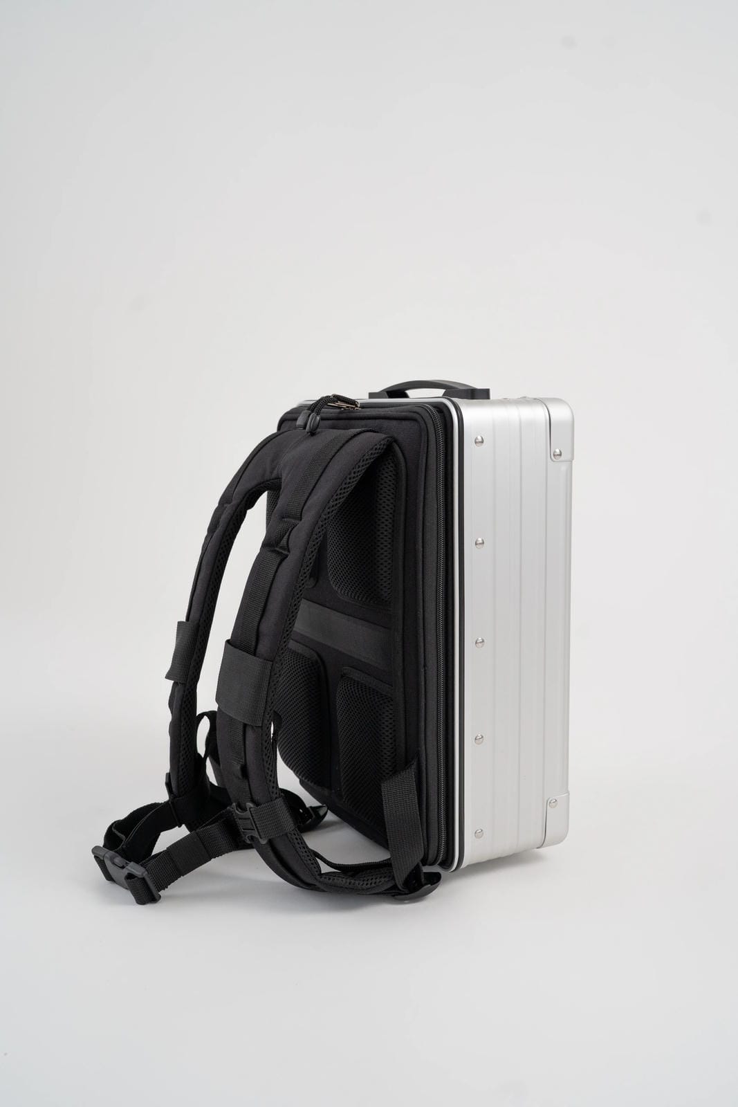 Black backpack with a silver suitcase attached on a white background