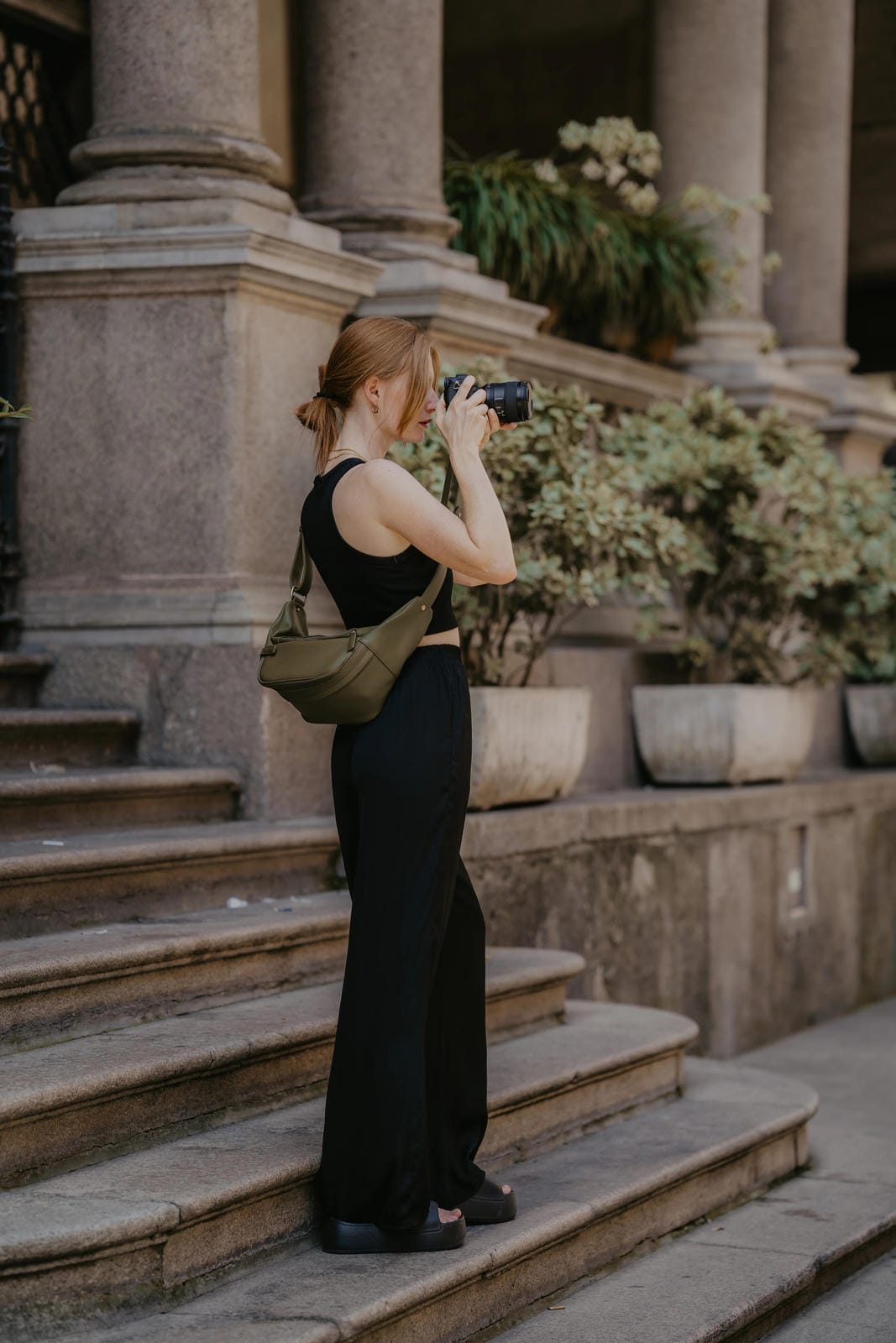 Woman taking a photo with a camera on stone steps in an urban setting