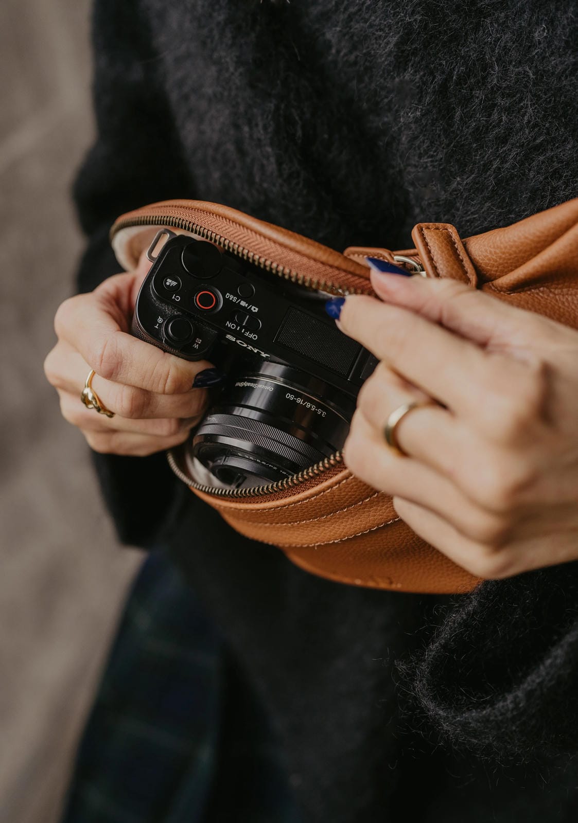 Person holding a camera with a brown leather case.