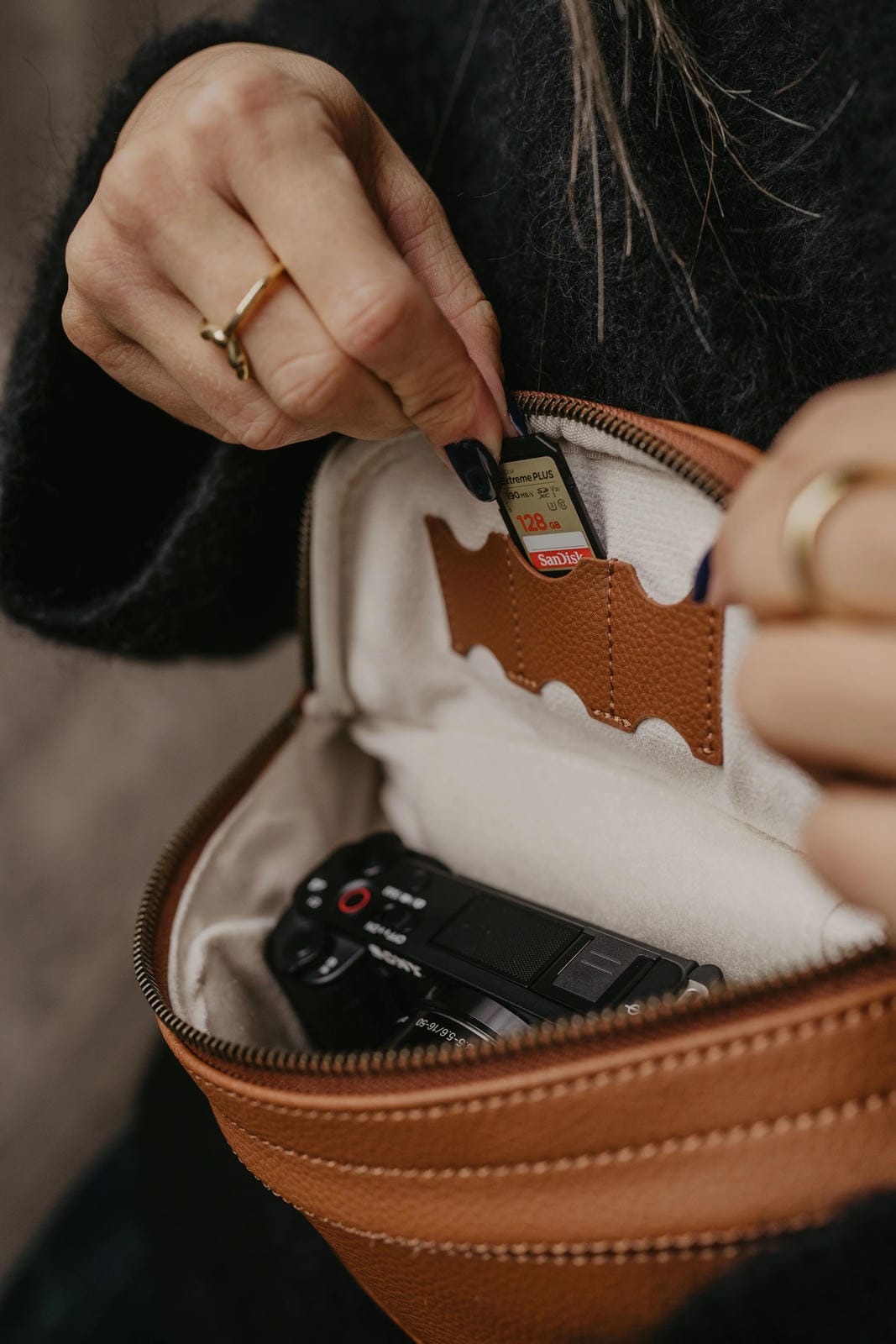 Person opening a brown leather case to reveal a camera inside