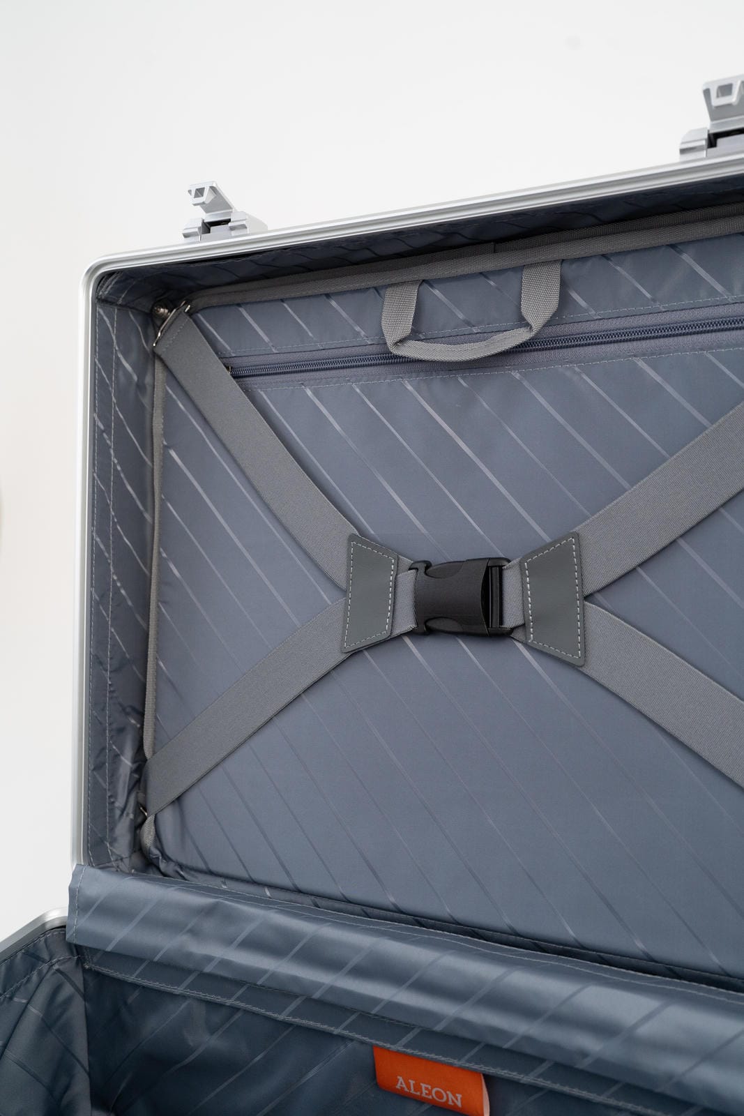 Close-up of a gray suitcase with a strap on a light gray background