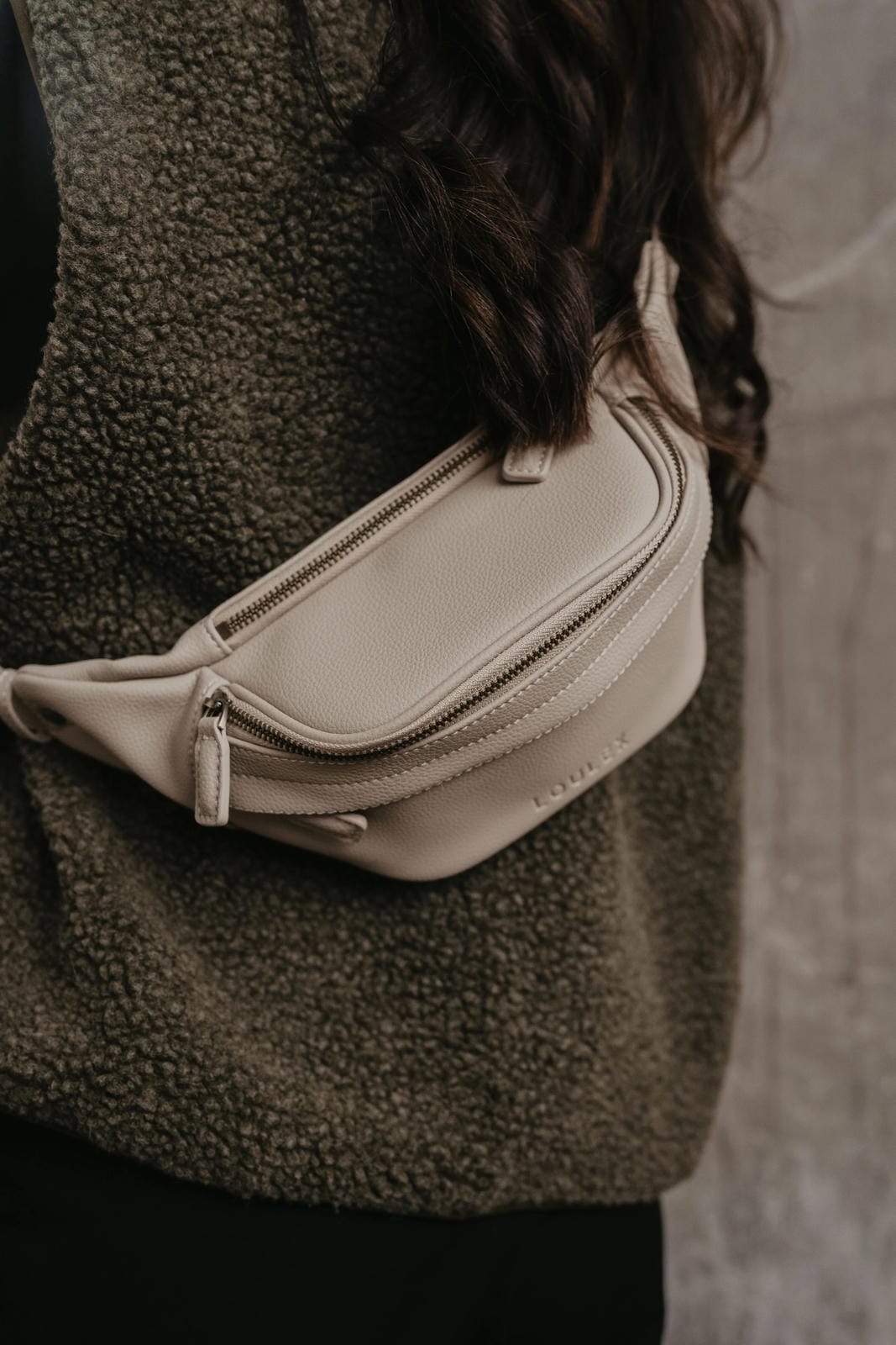Person wearing a beige waist bag with a blurred background