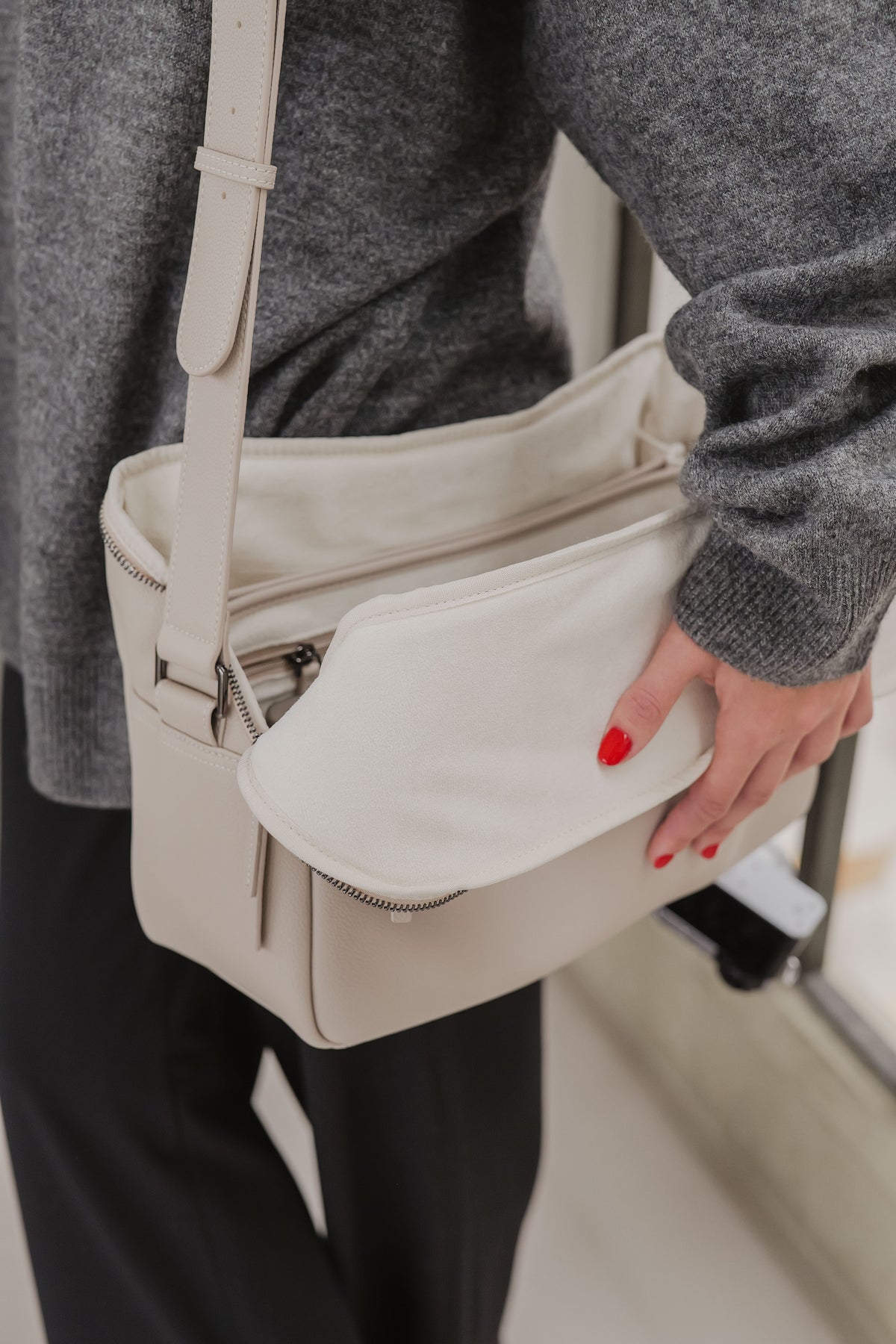 Person holding a beige handbag with a blurred background