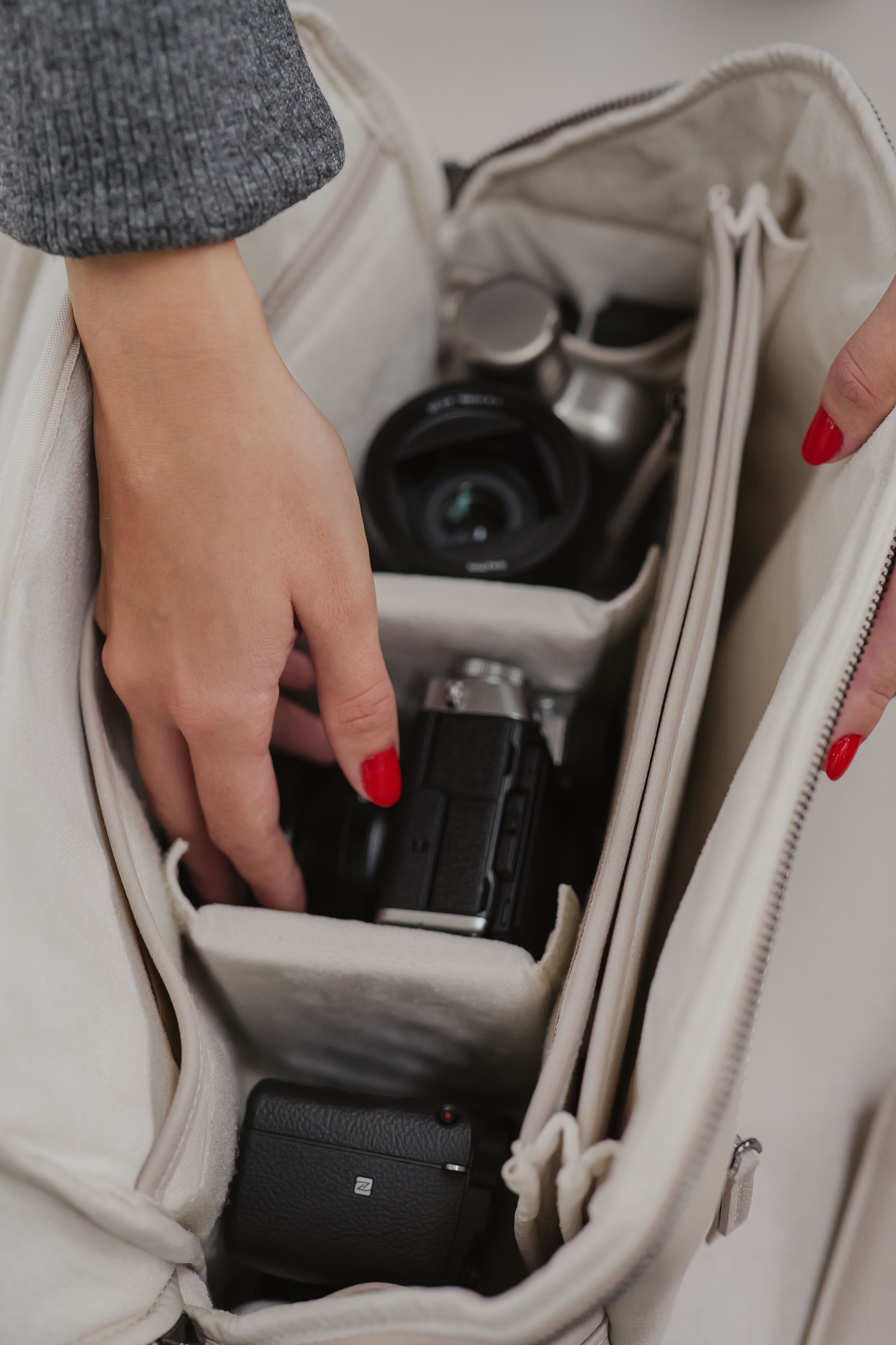 Person organizing camera equipment inside a beige bag