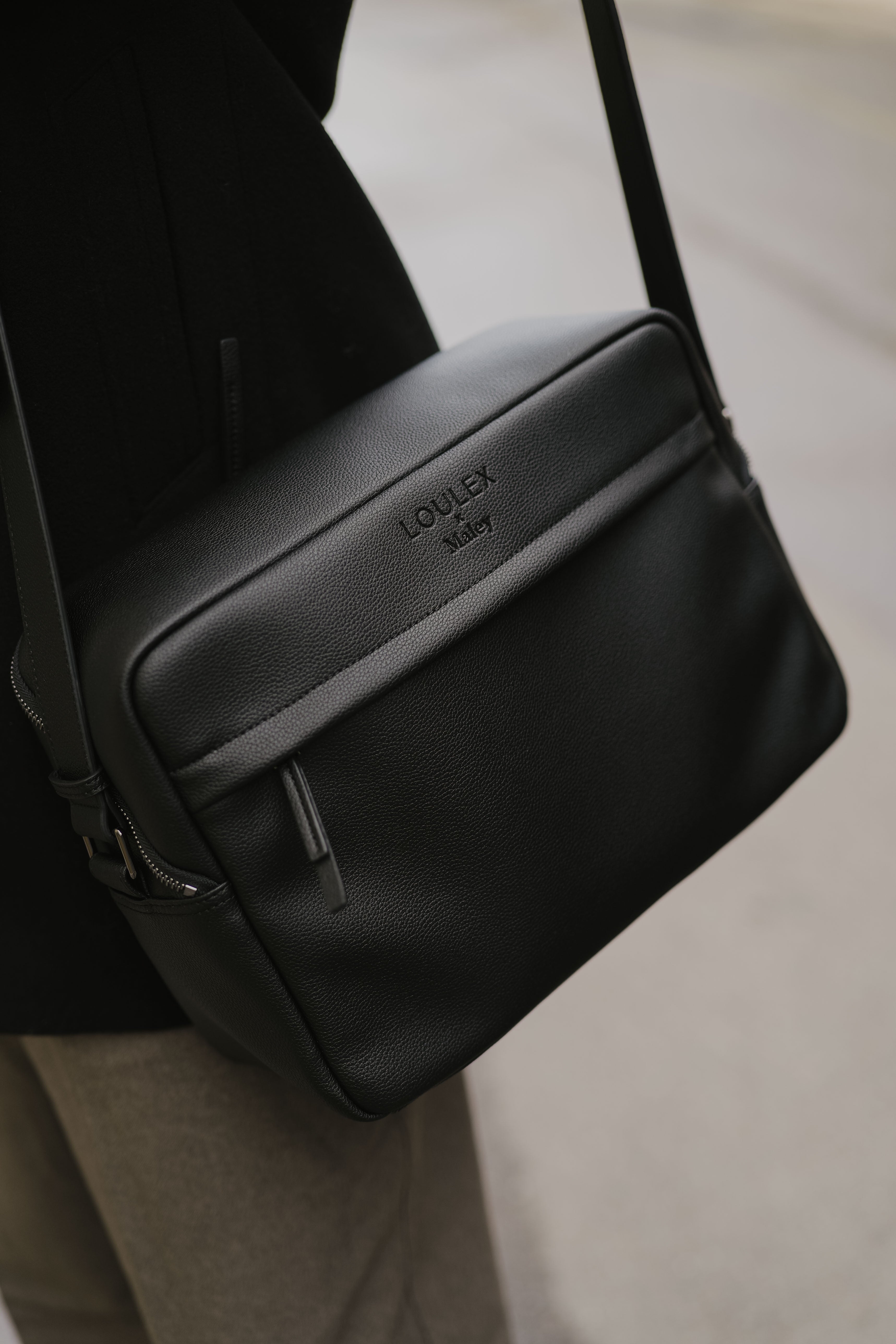 Black leather bag with 'LOEWE' branding worn over a shoulder.