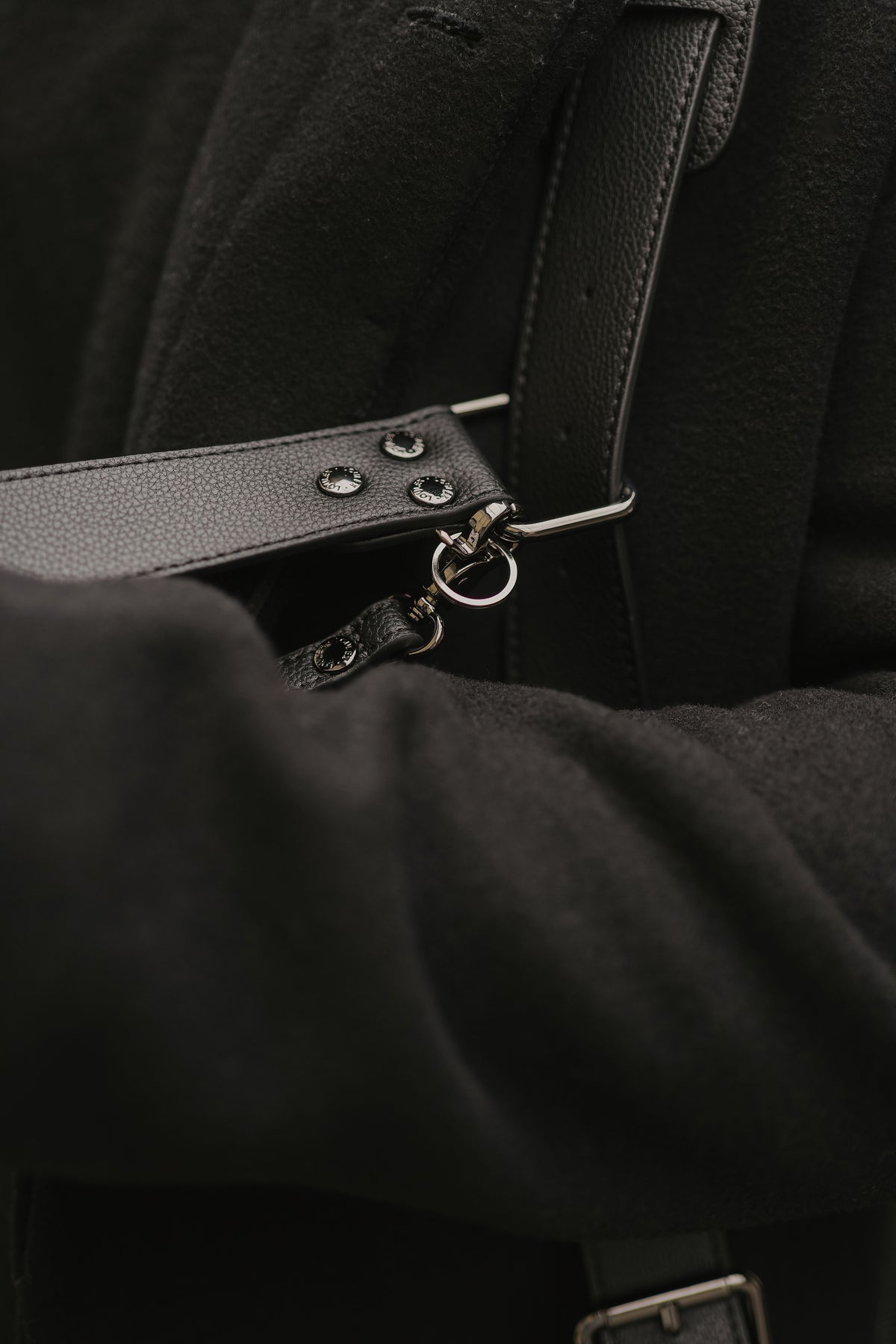 Close-up of a black leather strap with metal hardware on a dark background