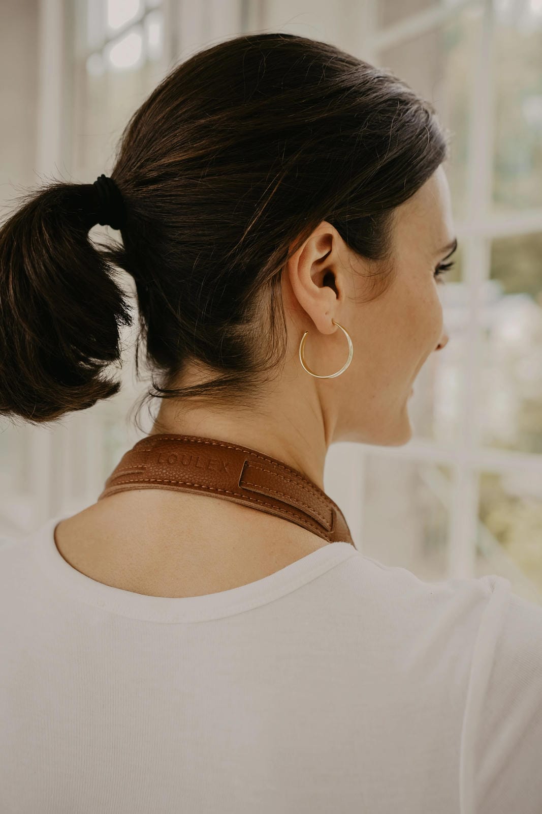 Woman wearing gold hoop earrings with a blurred background
