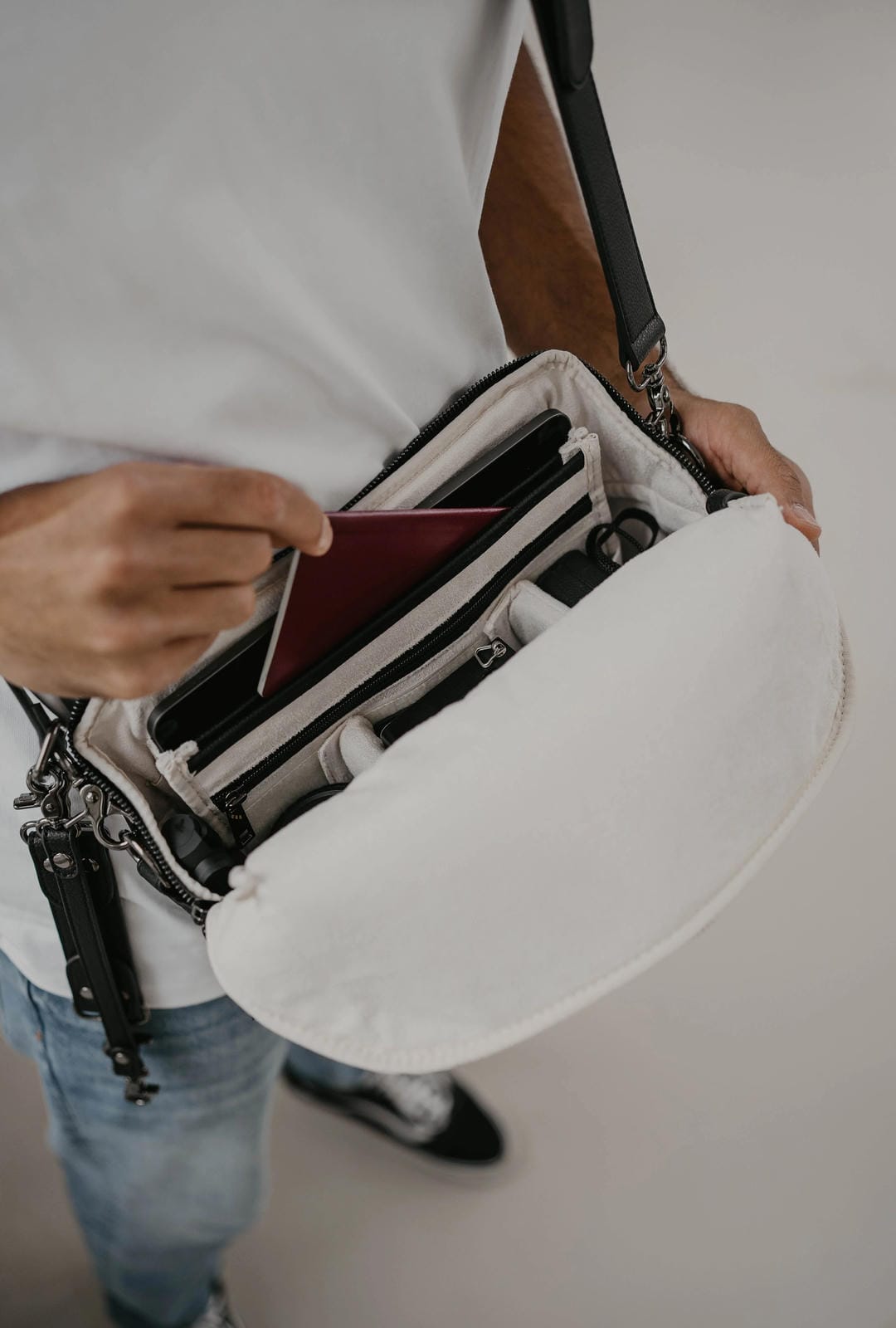 Person holding a white crossbody bag with a neutral background