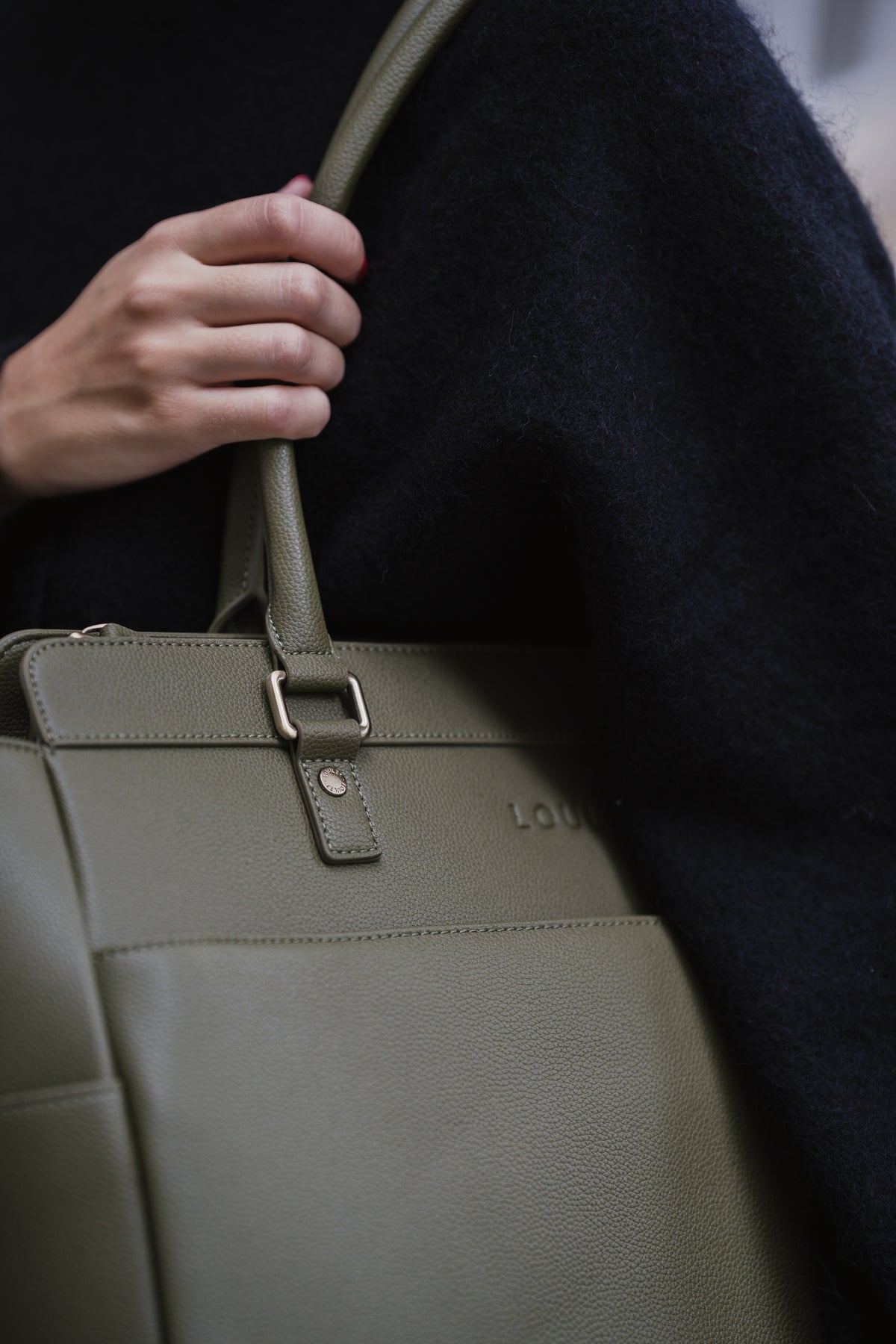 Person holding a green leather bag with a dark background