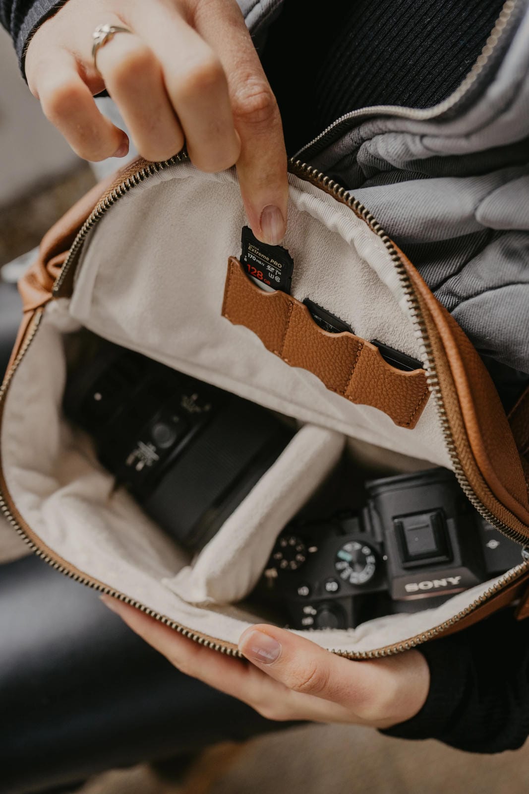 Person holding a camera bag with a camera inside