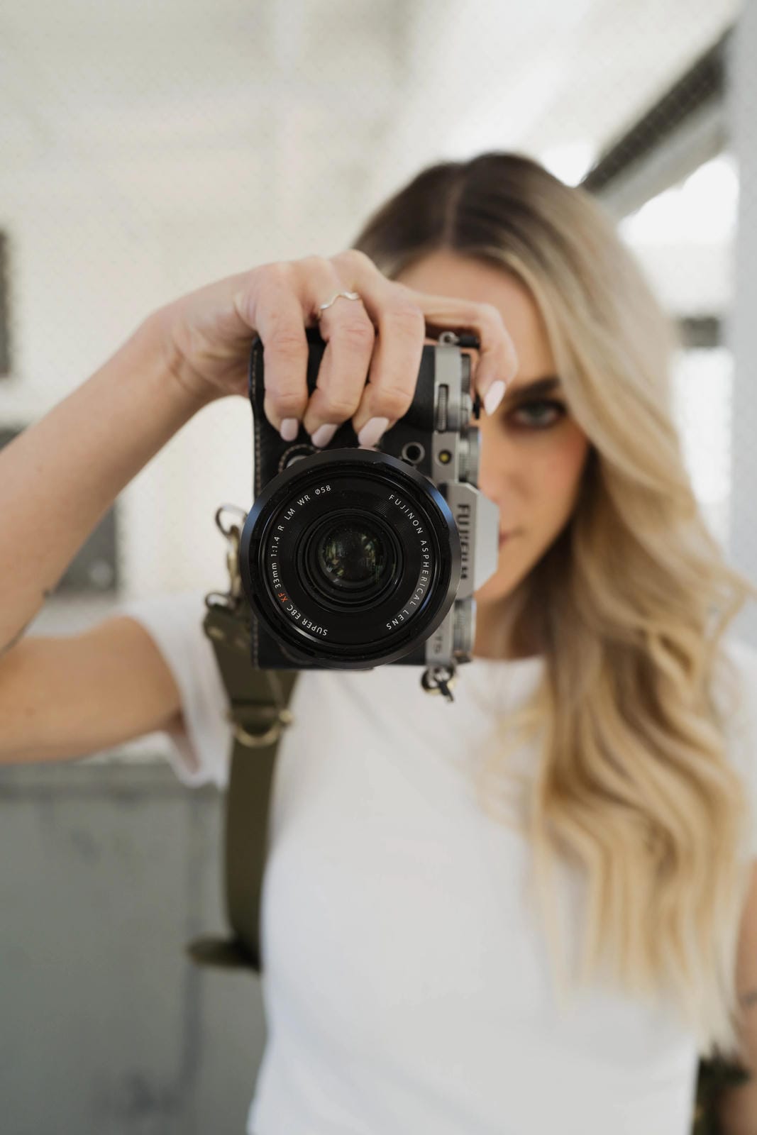 Woman holding a camera up to her face with a blurred background