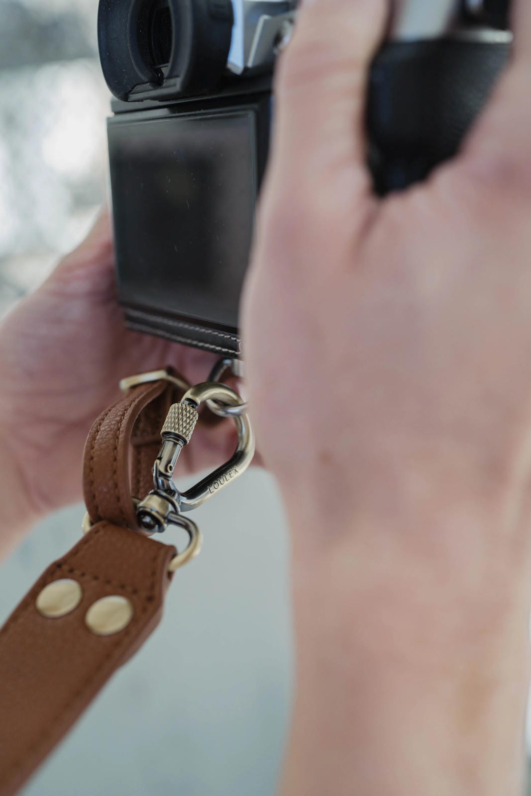 Close-up of a hand holding a leather keychain with a blurred background