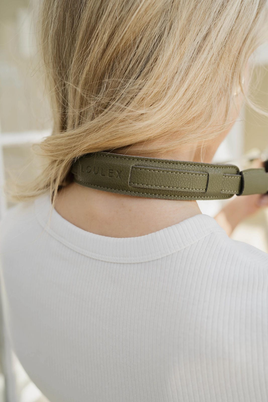Person wearing a green headband with a brand logo on a neutral background