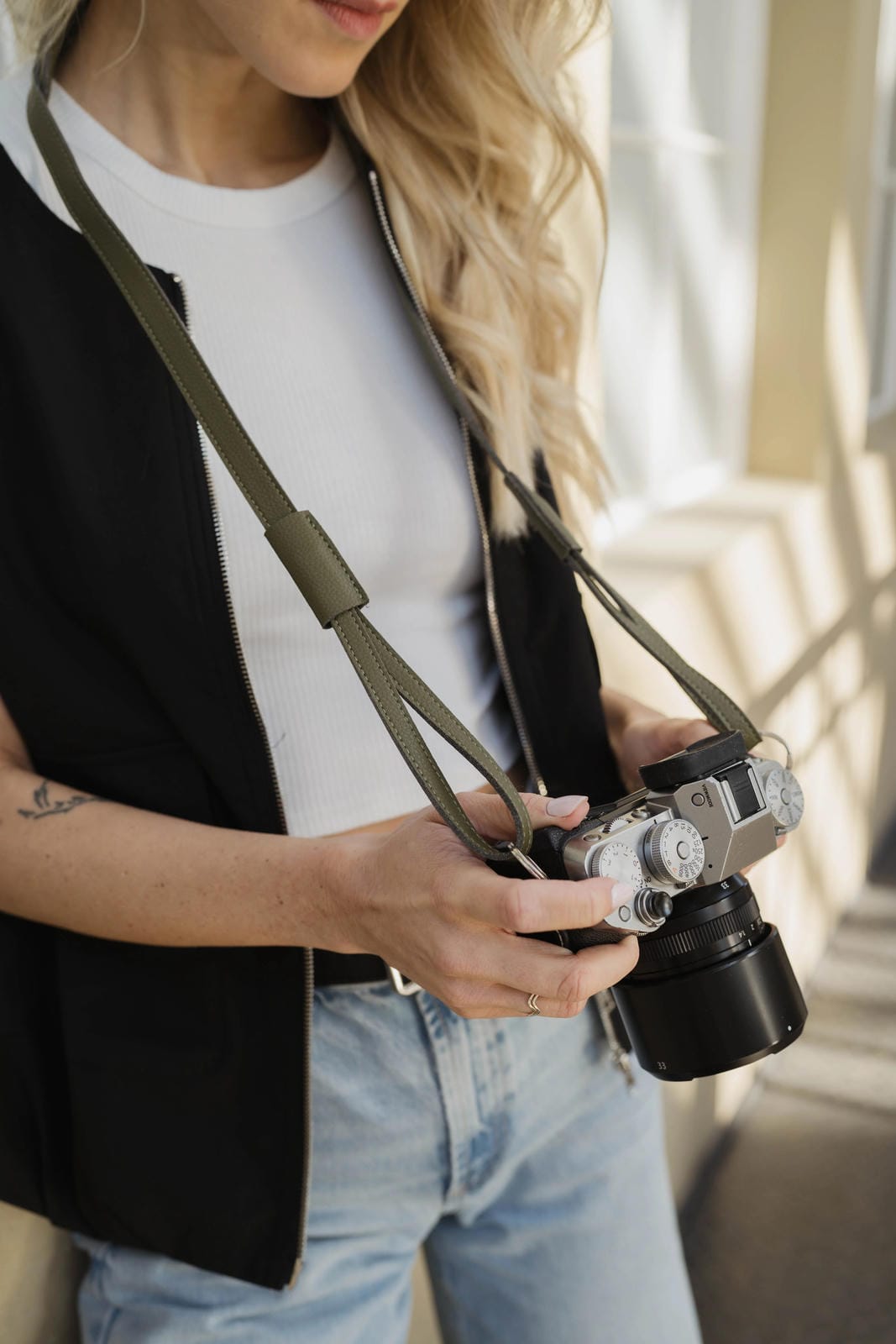 Person holding a camera with a strap, blurred background