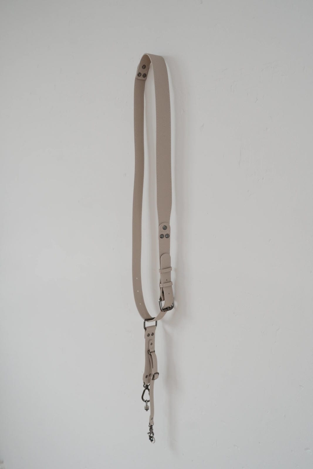 Beige leather strap with metal hardware on a white background