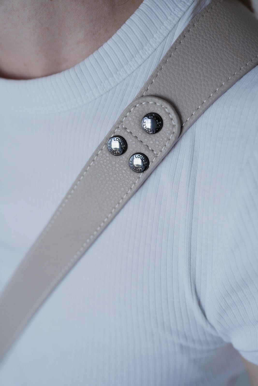 Close-up of a beige strap with metallic buttons on a white background