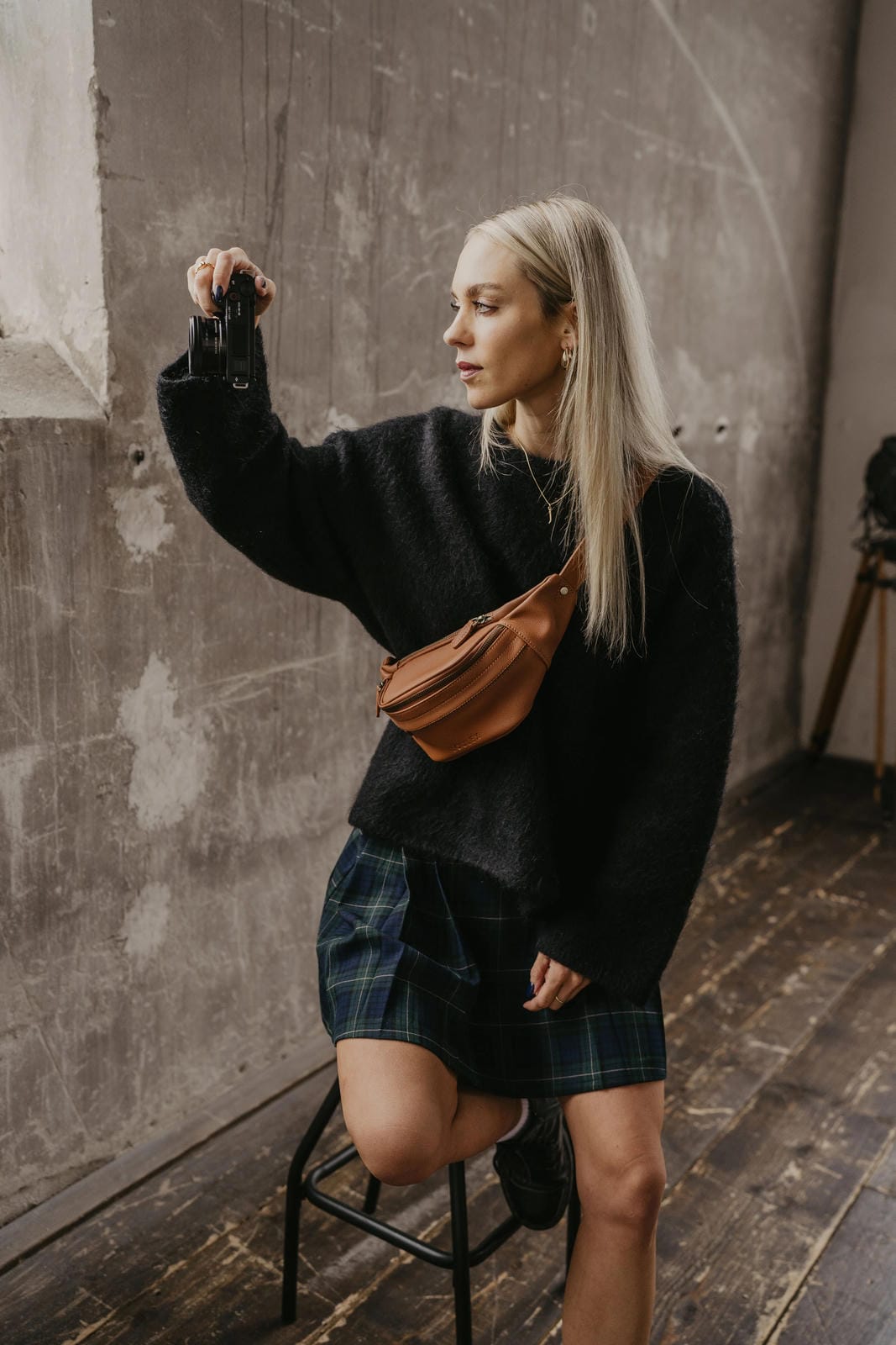 Woman taking a selfie in a casual setting with a textured wall background
