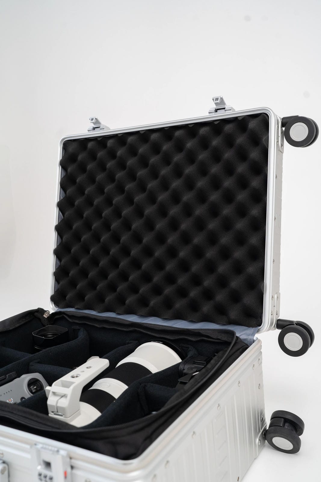 Silver hard-shell case with black interior foam, containing white cylindrical objects on a white background.
