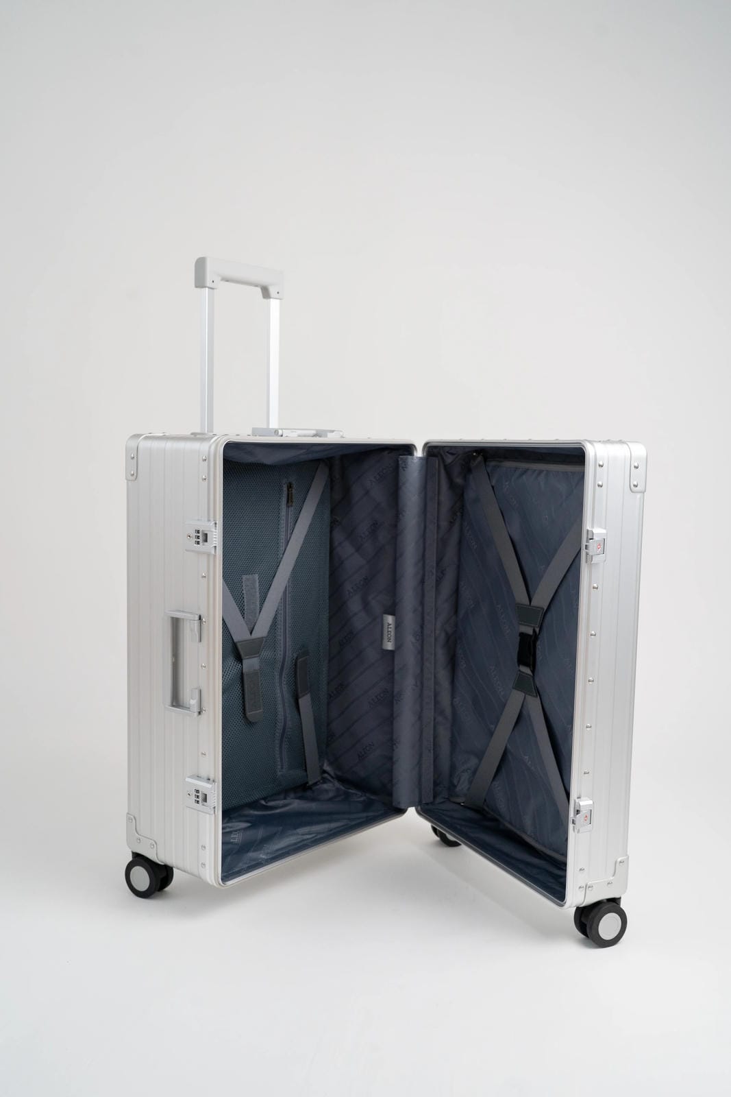 Open silver suitcase with wheels on a white background