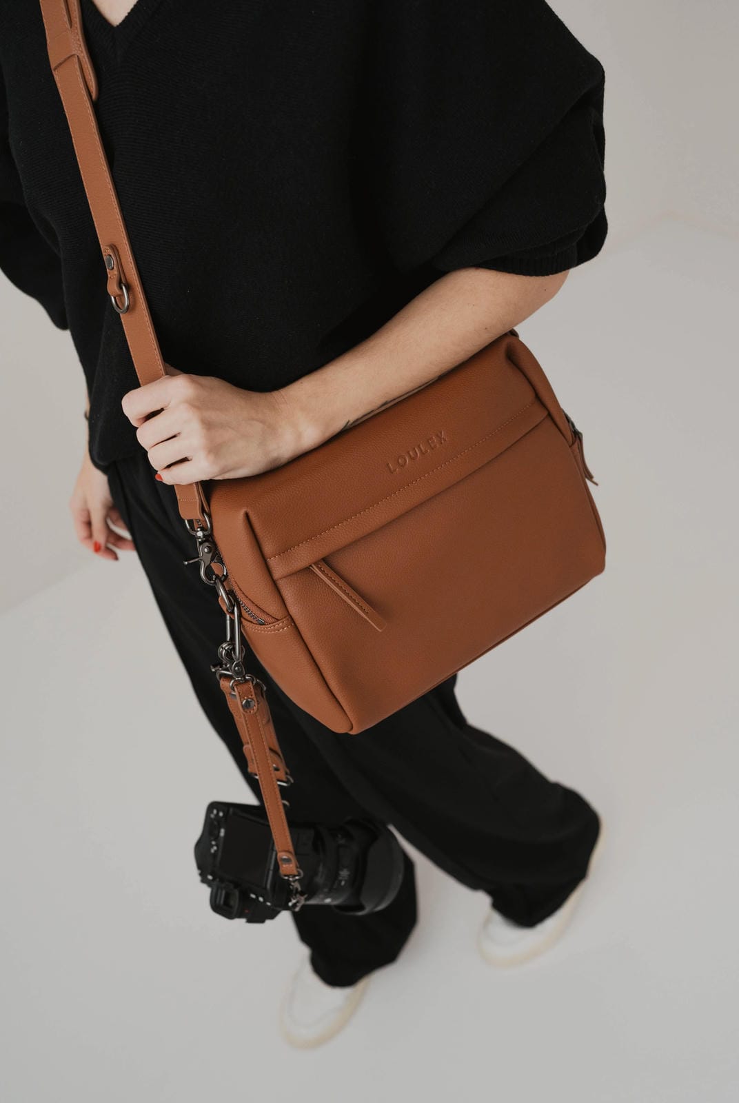 Person holding a brown leather bag with a blurred background