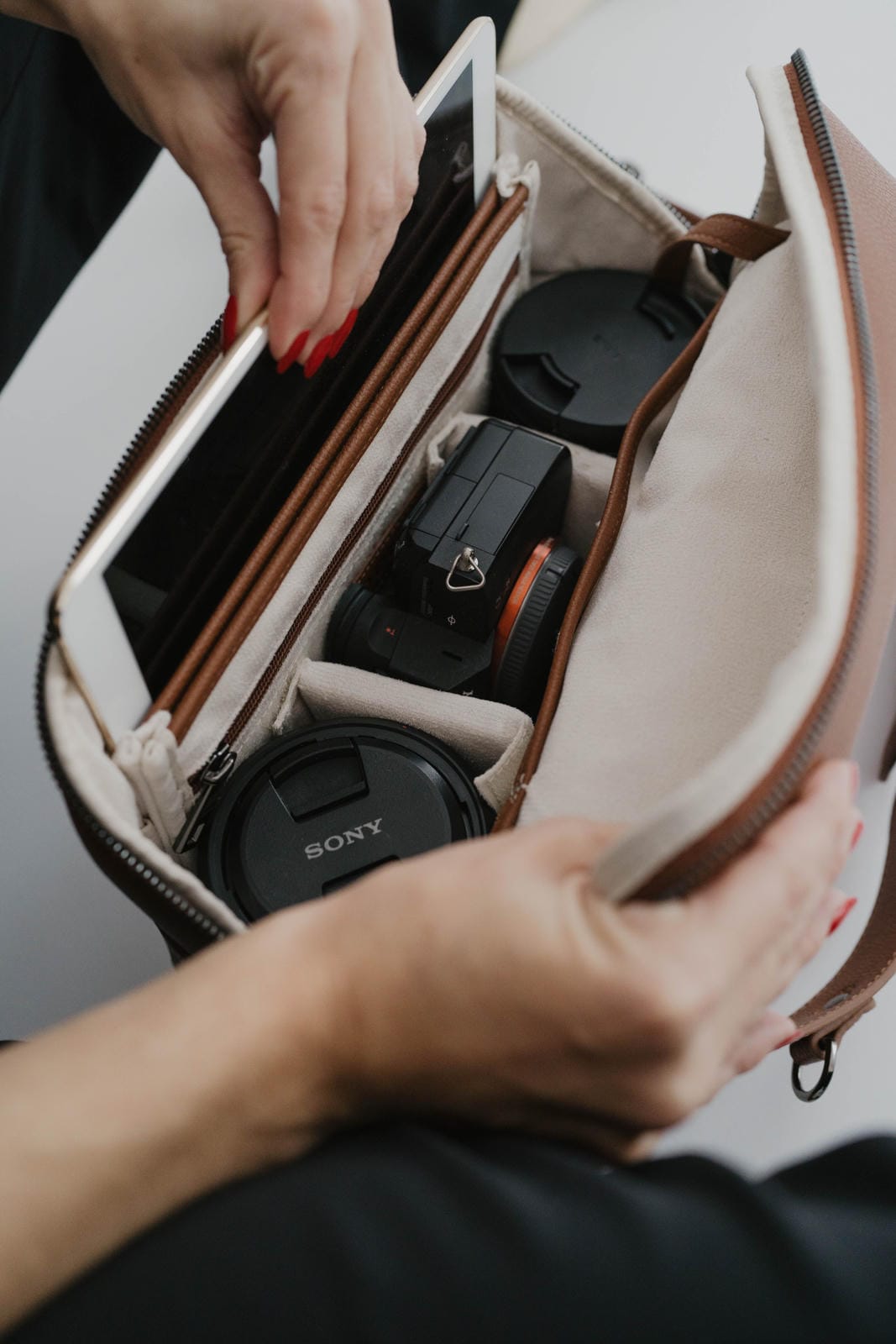 Person opening a camera bag with a Sony camera inside