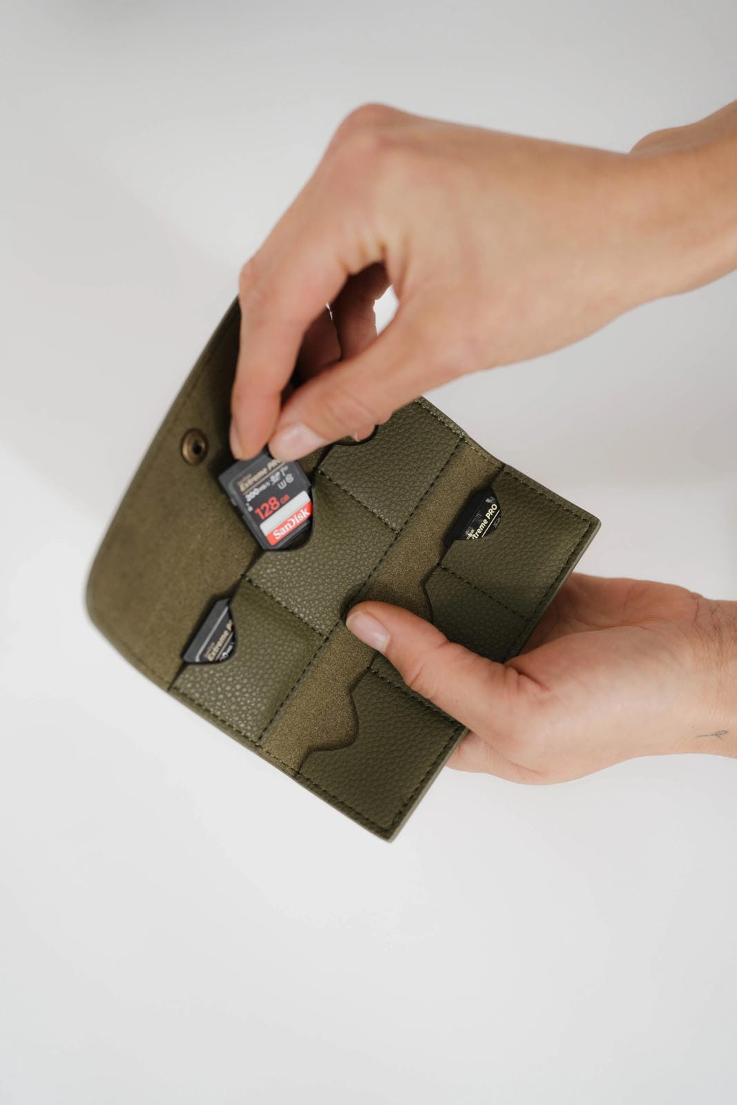 Person holding a green wallet with a white background