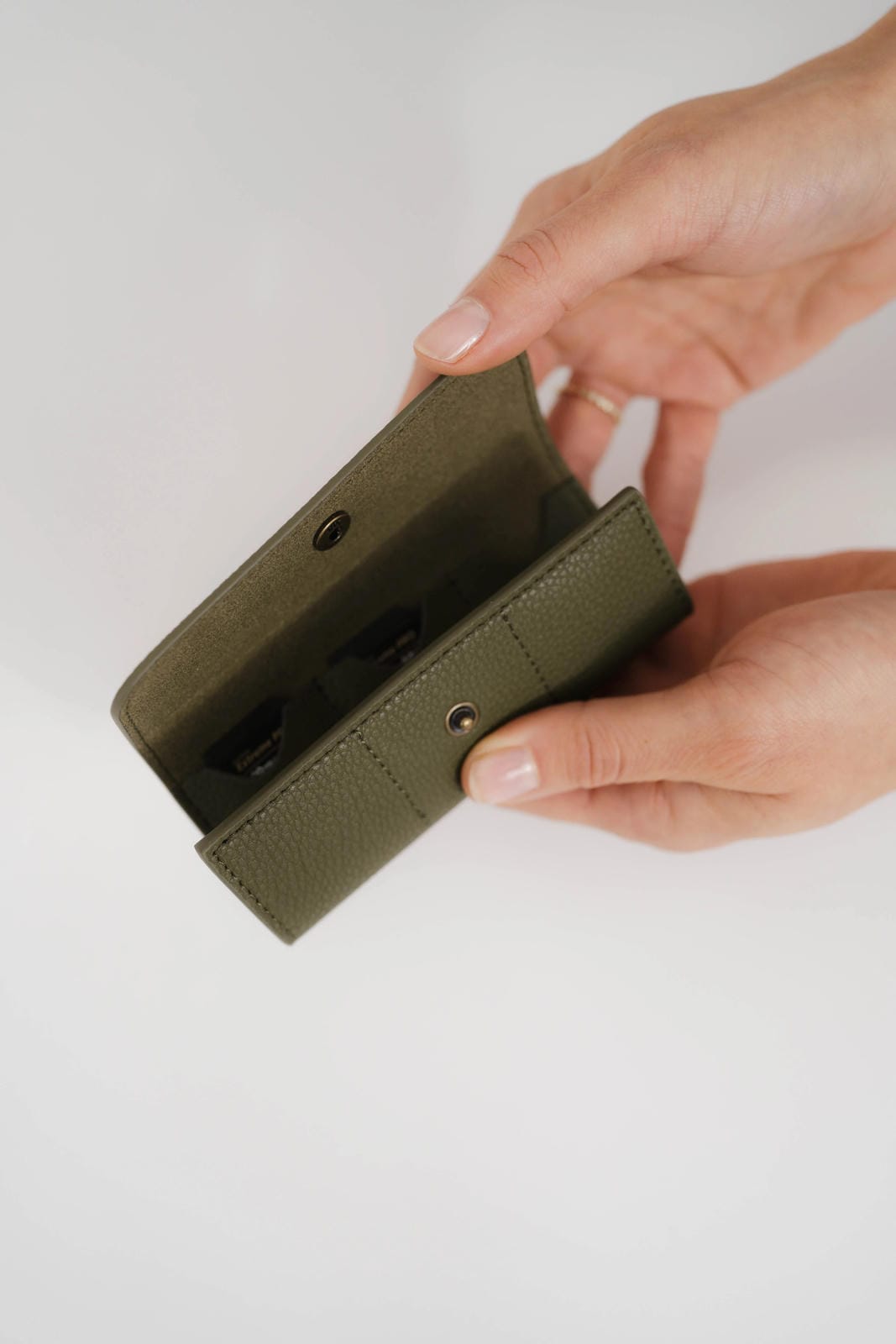 Hand holding a green phone case on a light background