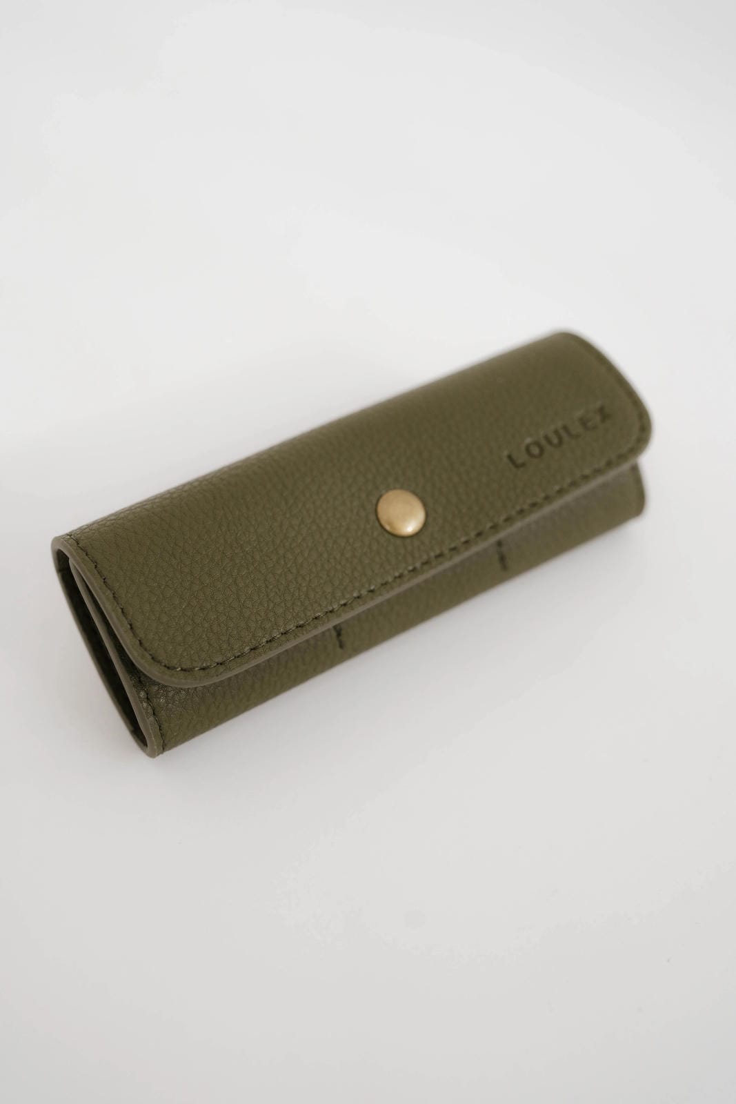 Green leather wallet with a gold button on a white background