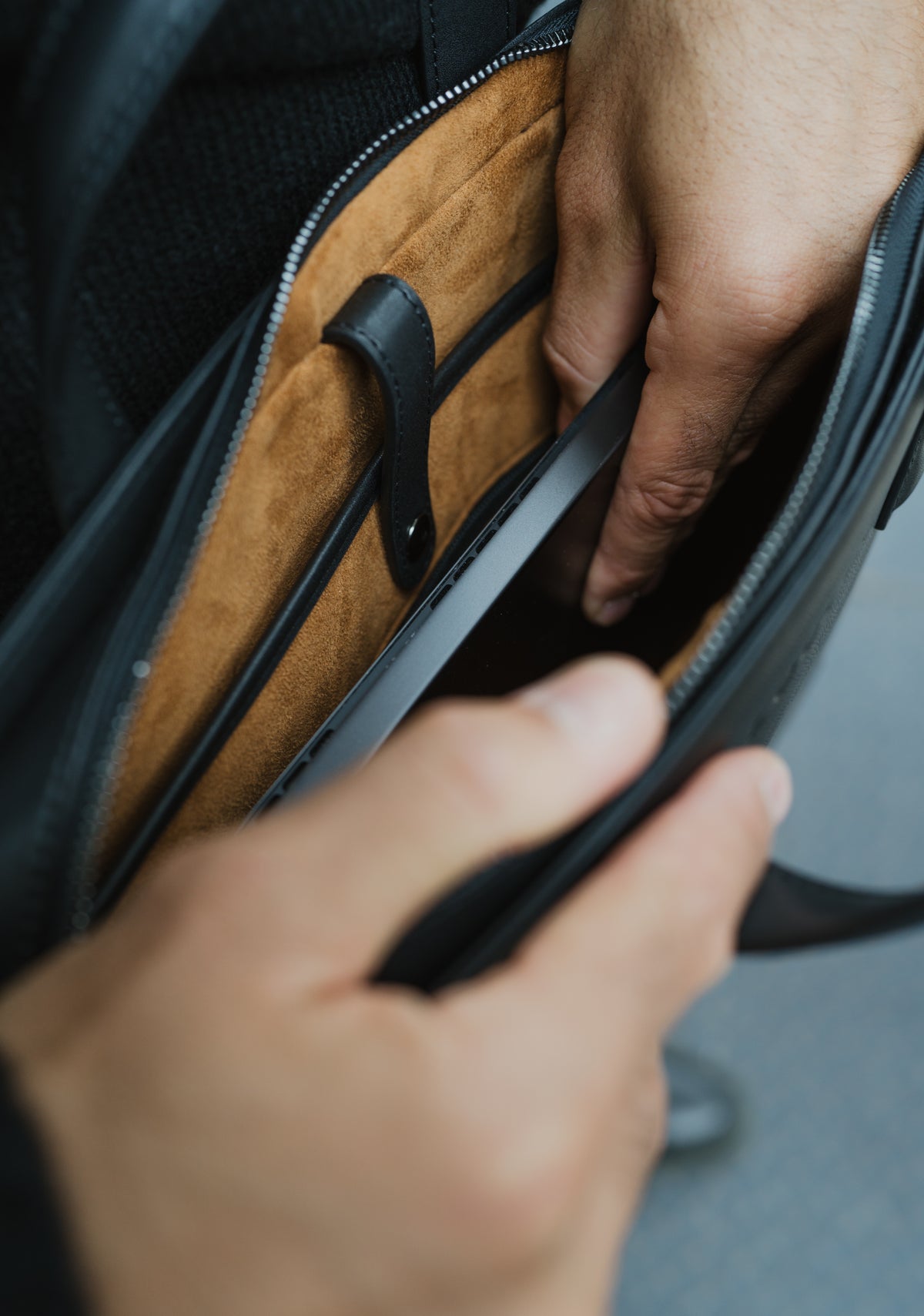 Close-up of hands opening a black leather briefcase with a brown interior.