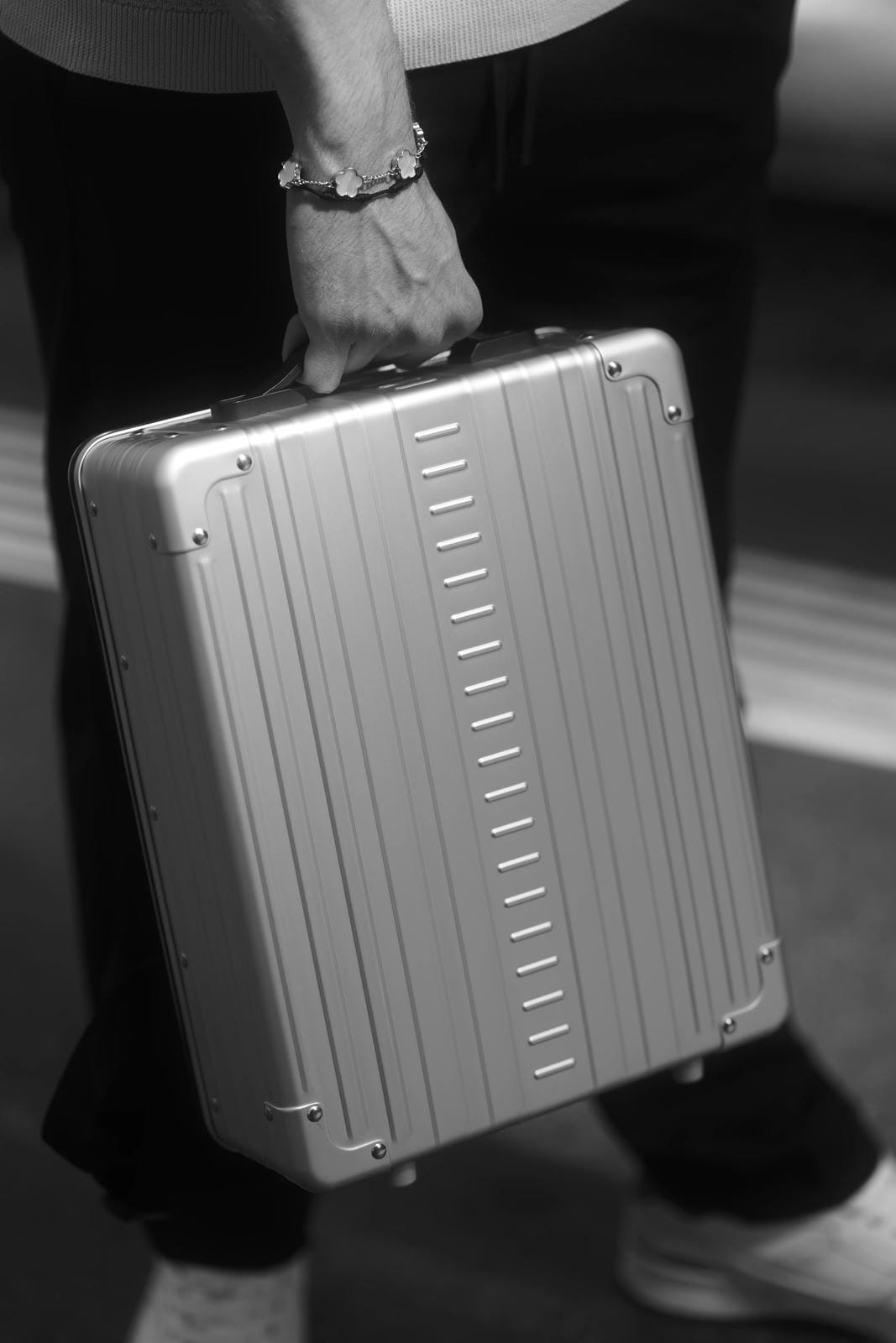 Person holding a metallic briefcase in black and white