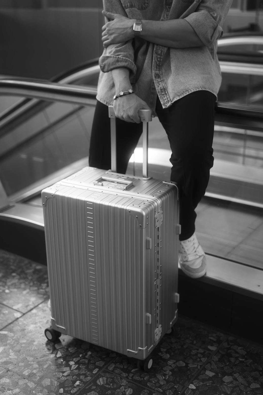 Person with a suitcase stepping off an escalator