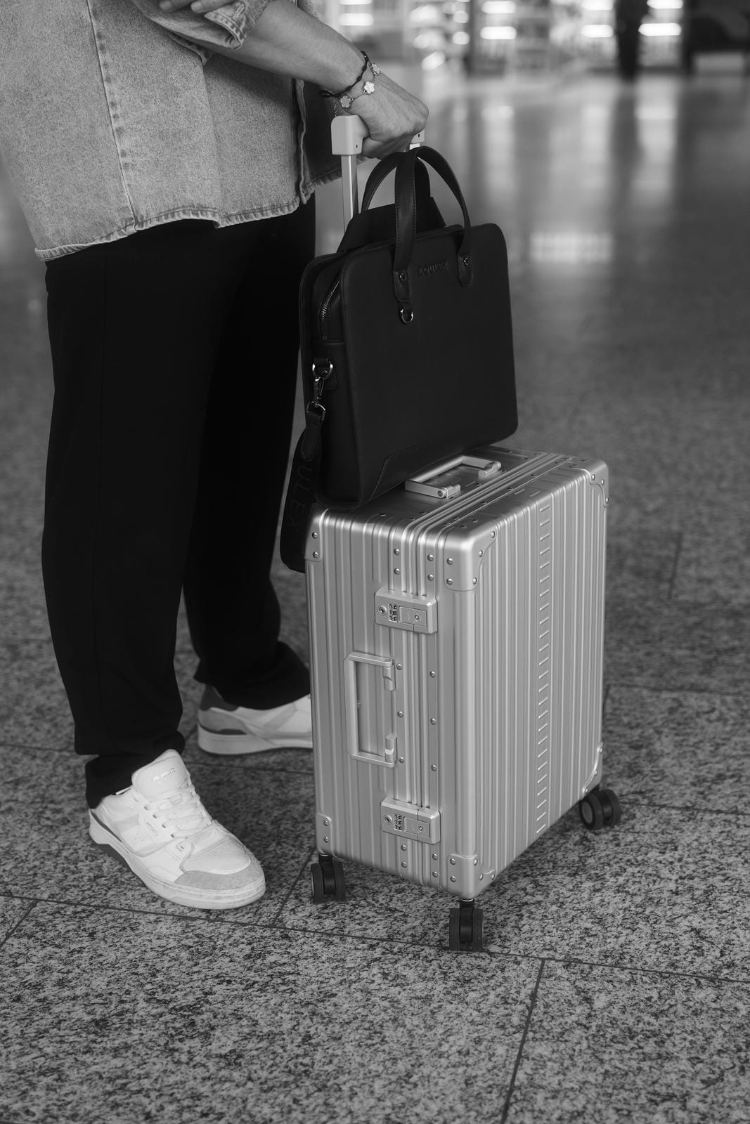 Person with a suitcase and handbag in an airport setting