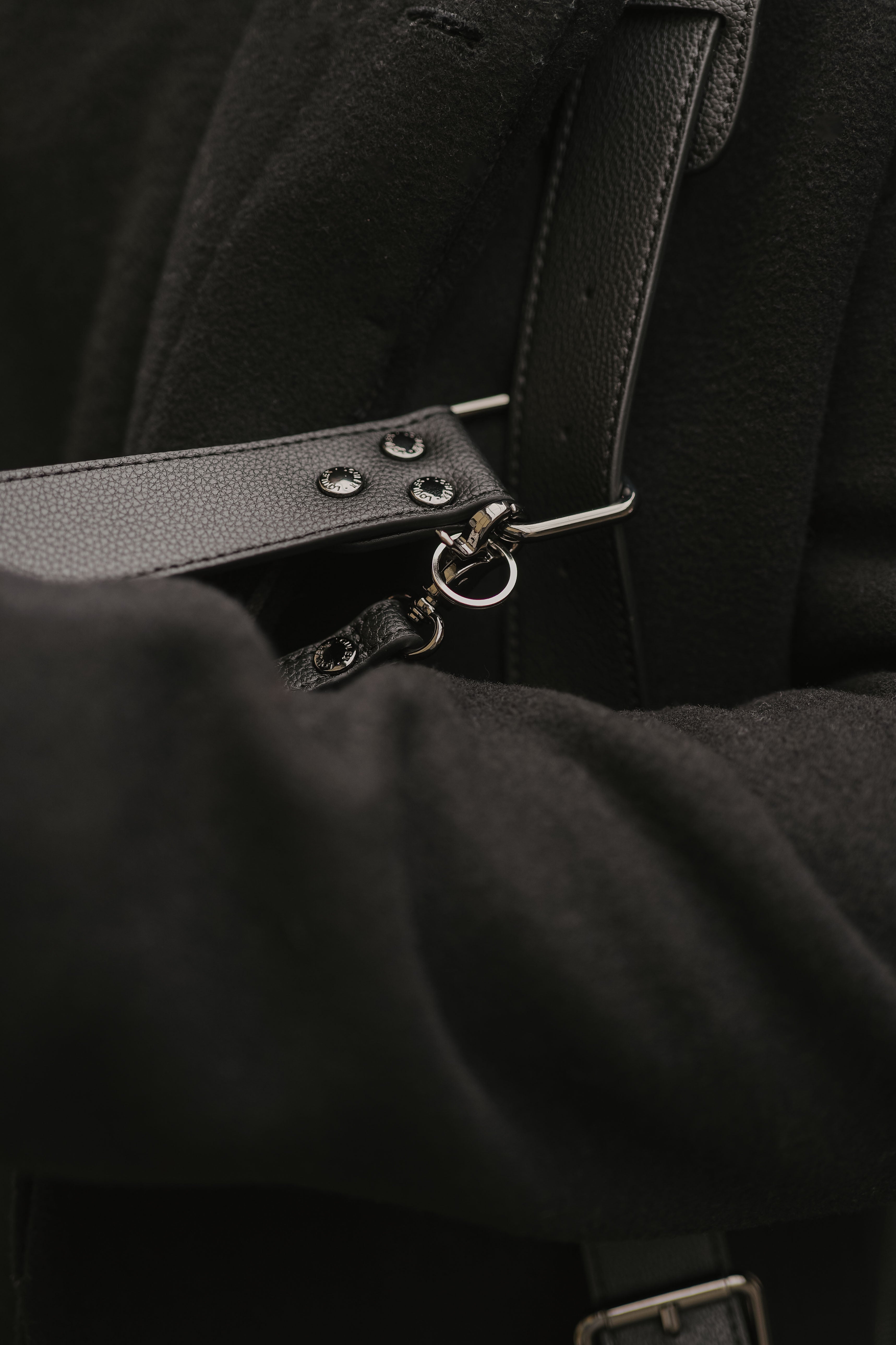 Close-up of a black leather strap with metal hardware on a dark background