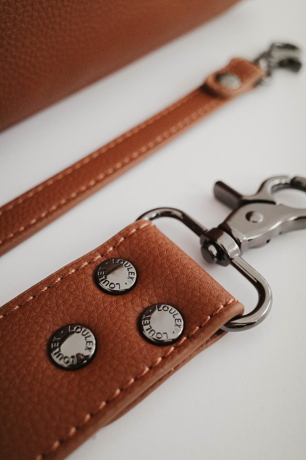 Brown leather keychain with metal clasp on a white surface
